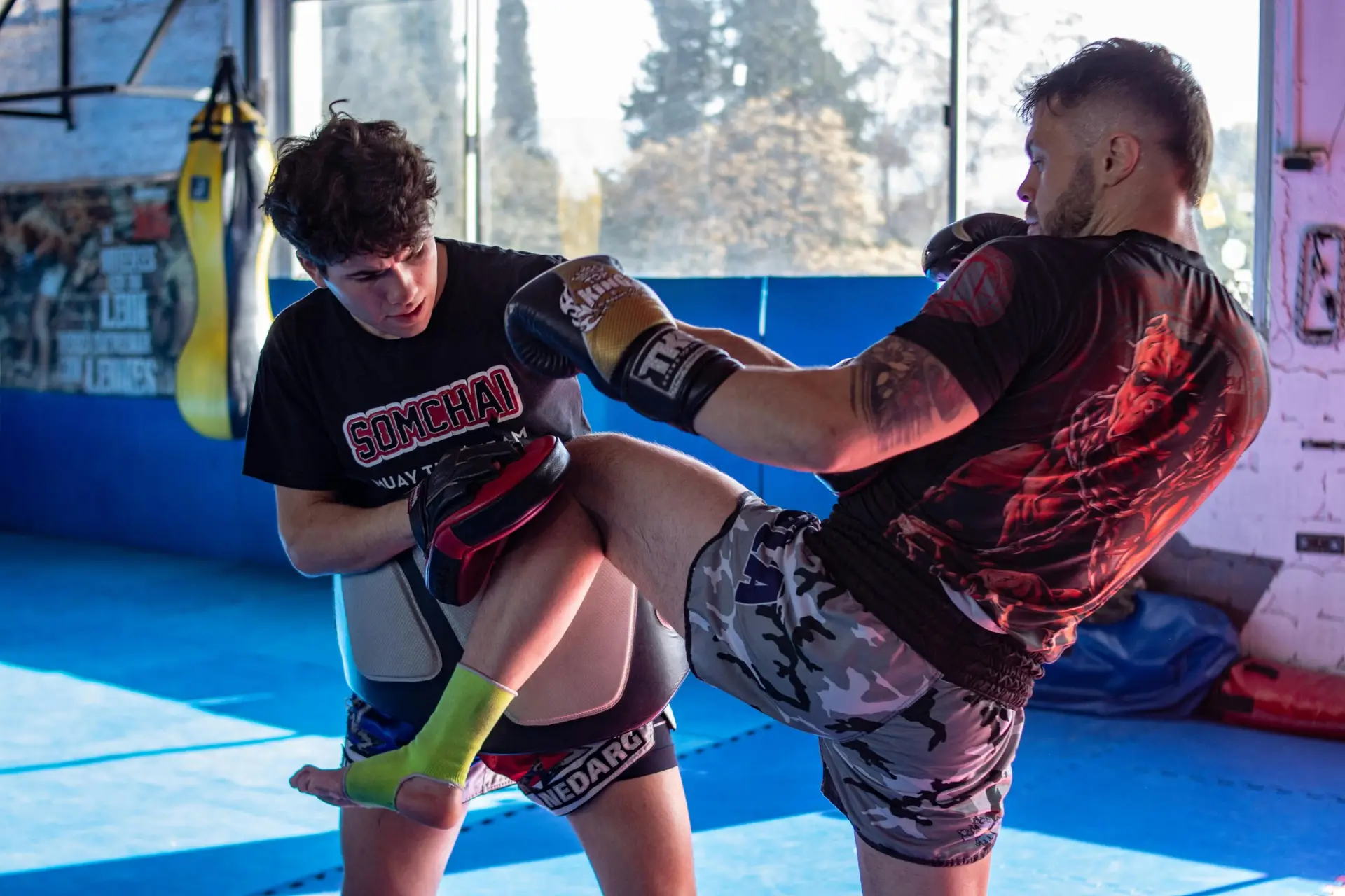 Two men engage in a focused kickboxing training session in an indoor gym.