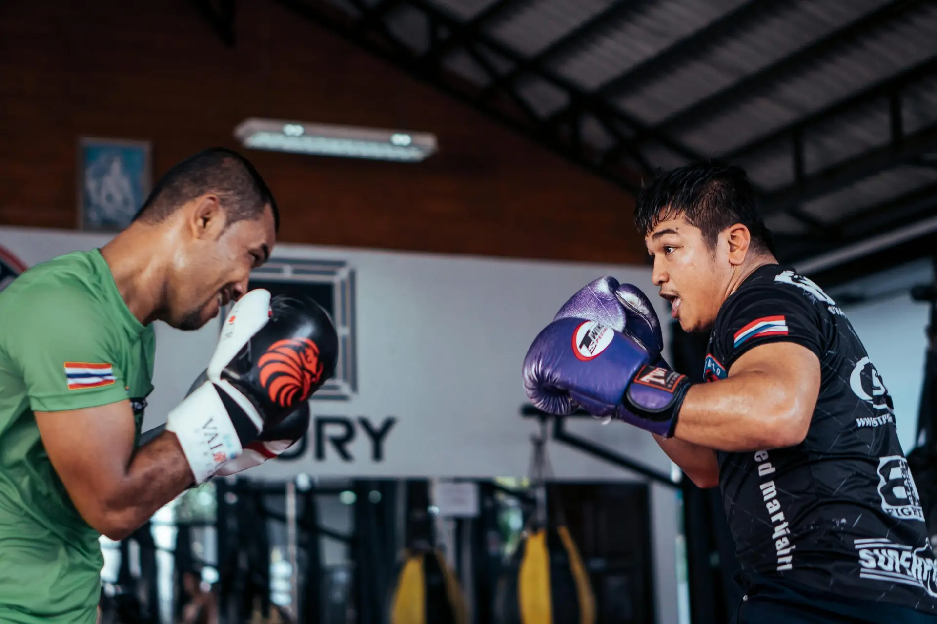 Two men train in a lively boxing session, showcasing skill and intensity indoors.