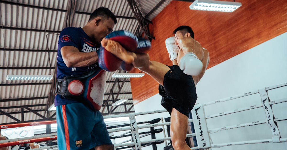 Two fighters engage in a dynamic Muay Thai training session inside a gym.